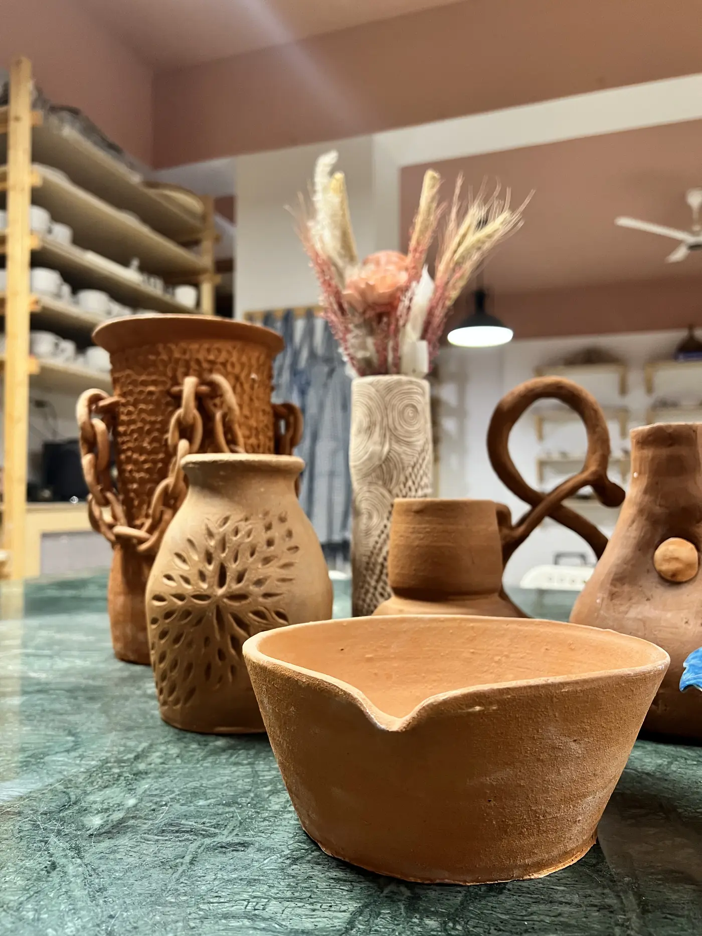 Drying ceramic pieces resting on wooden shelves in Kalapatti studio